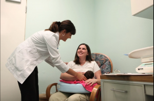 Physician helping woman breastfeed