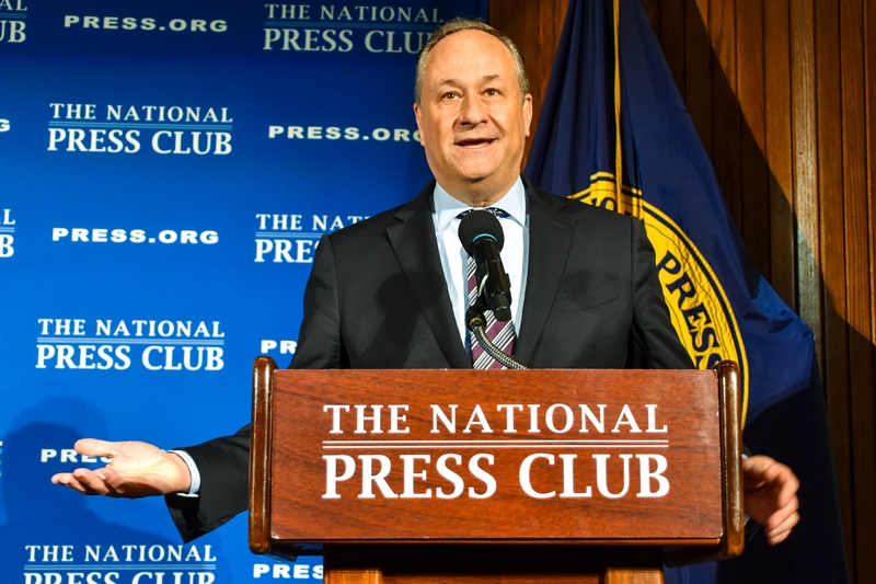 Second Gentleman Doug Emhoff stands at a podium while giving a speech.