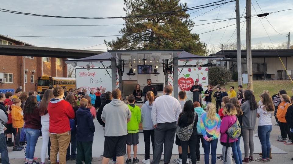 Image of crowd standing around a Teaching Kitchen stand.