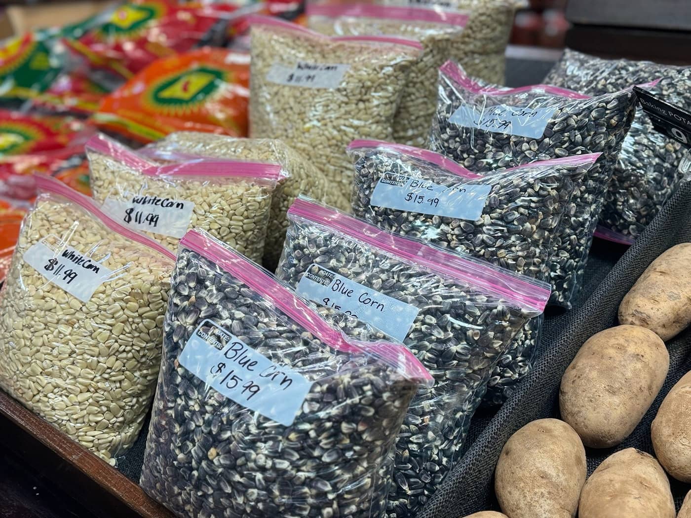 Plastic bags for sale that are filled with traditional Indigenous foods of white corn and blue corn.