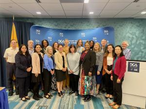 DGA meeting participants posing together in front of a DGA banner.