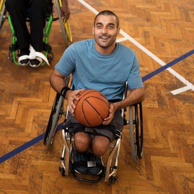 Jeff is in his wheelchair holding a basketball on the court