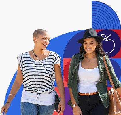 Two young women smile and laugh while walking together.