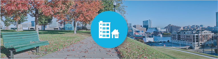 A buildings icon overlays a city park with red and brown leaves lying on a paved trail on an autumn day.