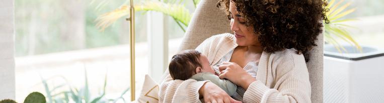 A mother holds her newborn baby and gives the baby a bottle.