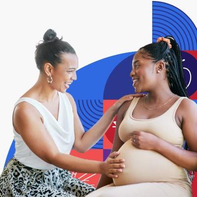 Una mujer de raza negra toca la panza de una mujer embarazada, también de raza negra.
