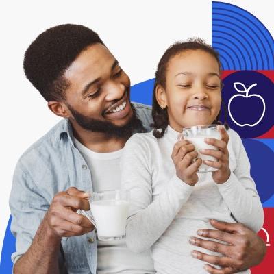 Un padre de raza negra y su hija beben juntos unos vasos de leche.
