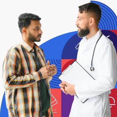 A young man with brown skin and short dark hair speaks with a male provider wearing a white lab coat.