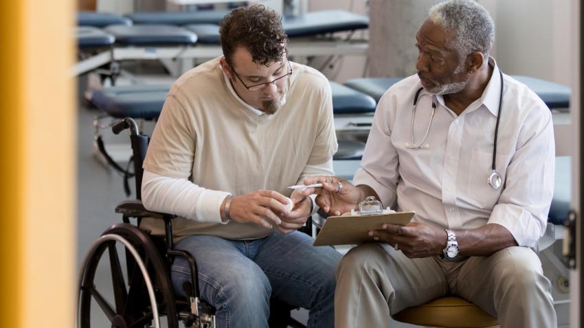 Man in wheelchair speaking with his provider.