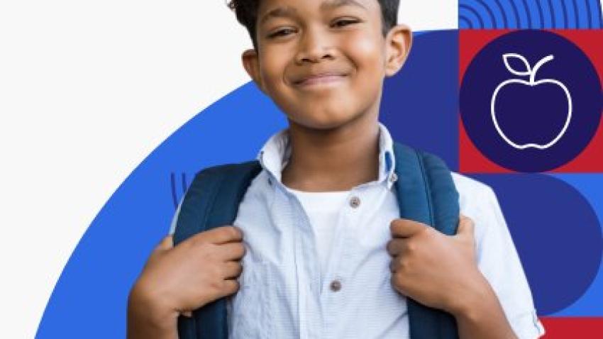 A young boy with dark hair and brown skin smiles at the camera and holds his backpack.