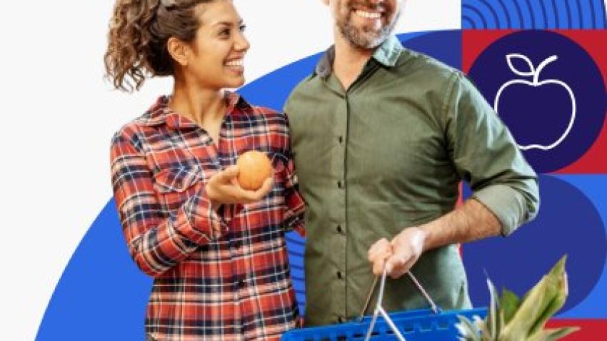 A smiling couple holding their basket full of groceries. 