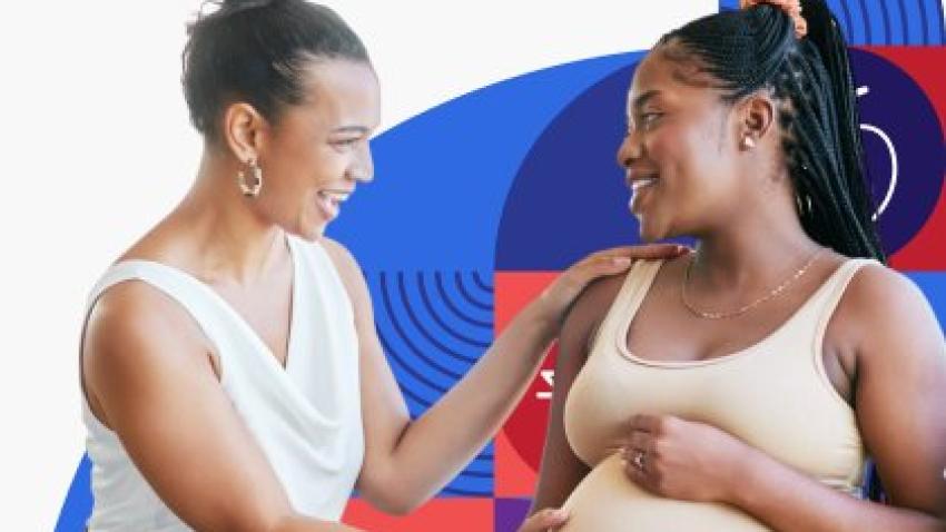 A pregnant woman smiles and talks with her friend, while her friend excitedly places her hand on her belly.