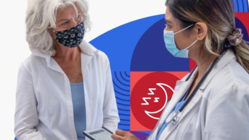 A doctor wearing a face mask takes notes while talking with a masked patient.