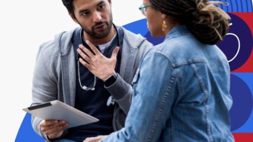 A medical professional is holding a medical chart and talking with a patient who is wearing glasses. 