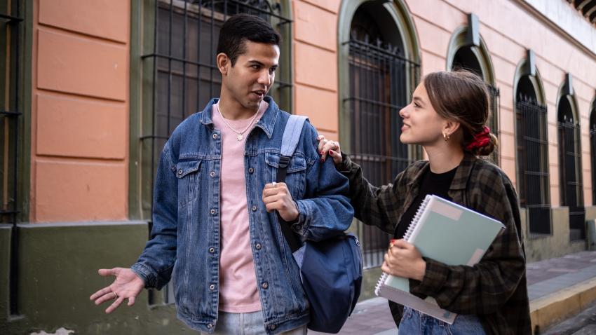 Two young adults having a conversation while walking together.